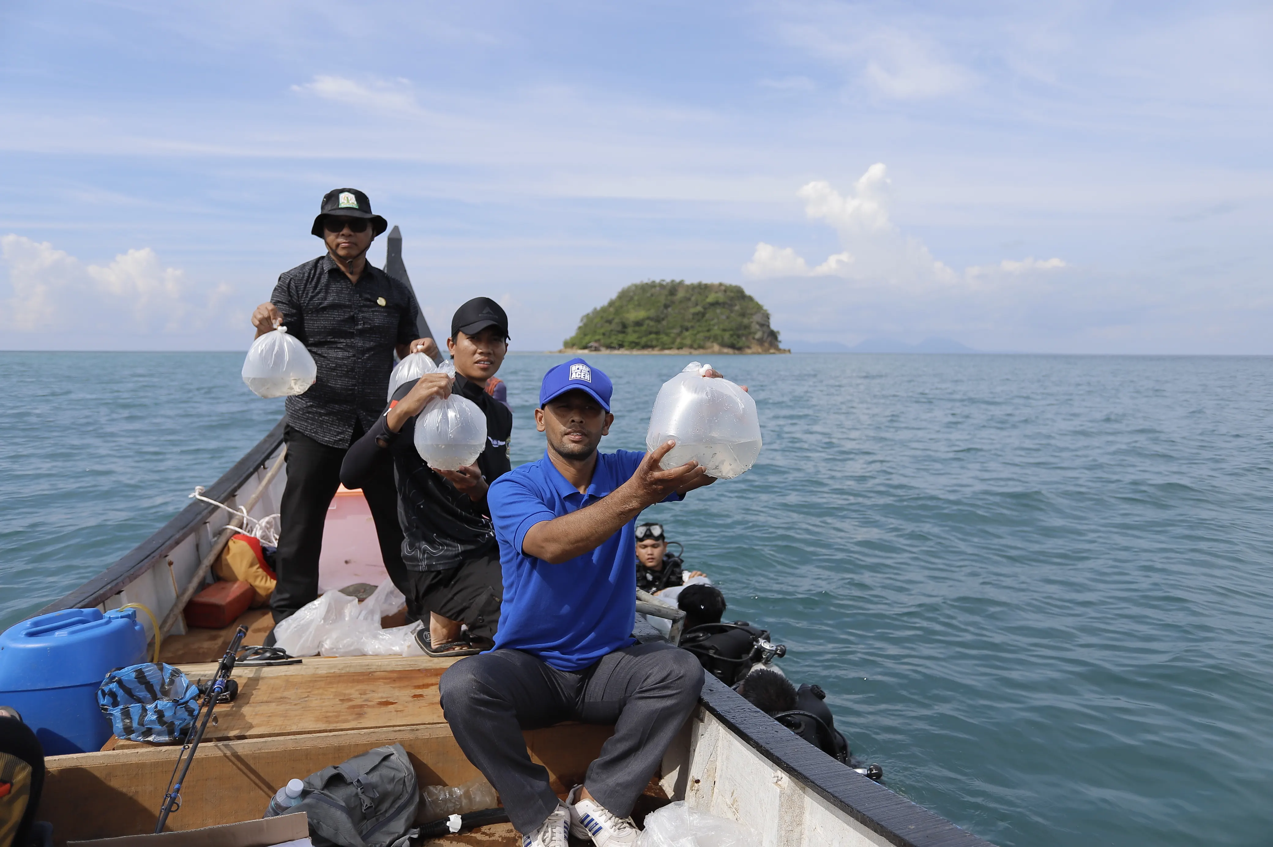 Group of young people smiling together on a boat, wearing wetsuits and diving gear, with the ocean and clear sky in the background. The mood is energetic and hopeful, reflecting teamwork and enthusiasm for marine conservation.